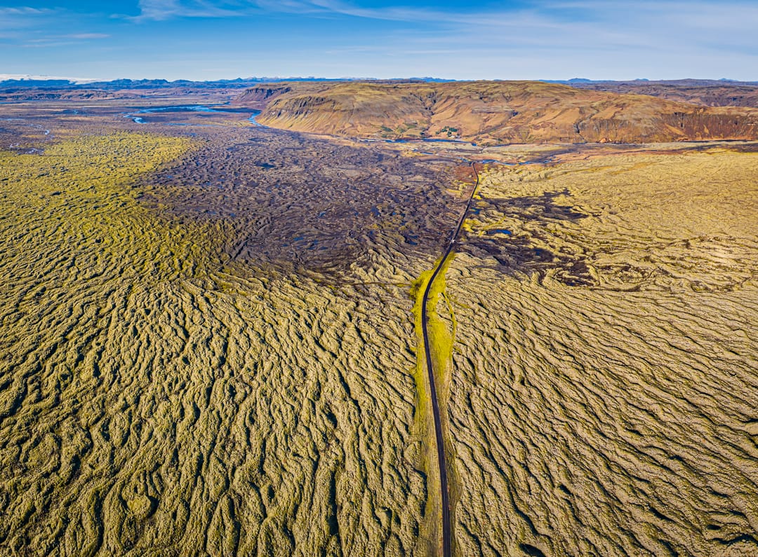Aerial view of a large lava field covered in moss with a blue sky