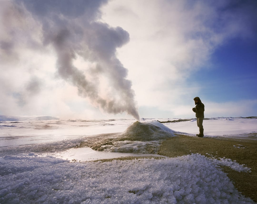 man standing by a geyser during winter
