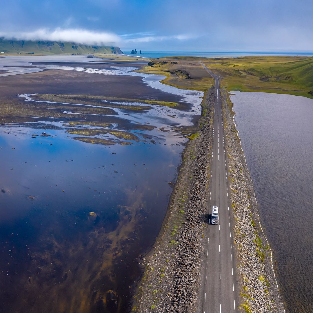 A car driving in the summer with Dyrhóley in the background