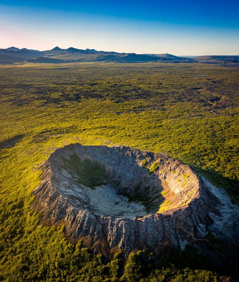 a deep volcanic crater in the middle of a lava field