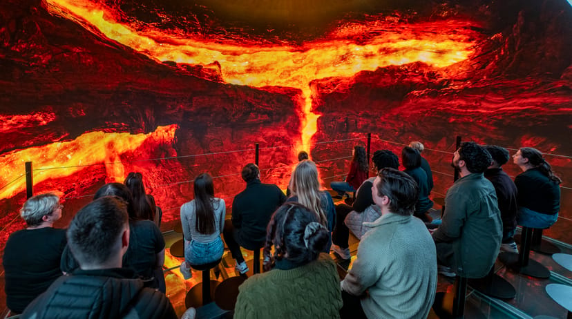 group of people surrounded lava in the into the volcano exhibit in iceland