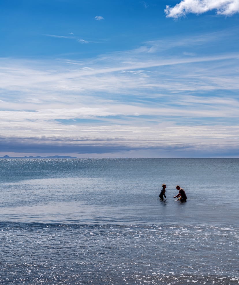 Father and son in the water at langisandur in iceland on a sunny day