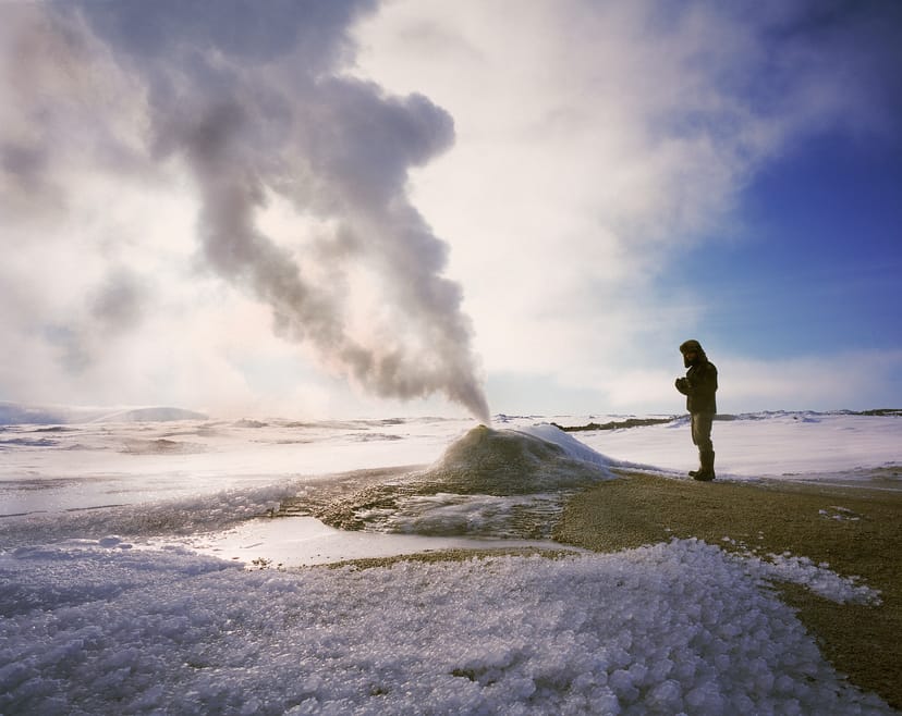 man standing by a geyser during winter